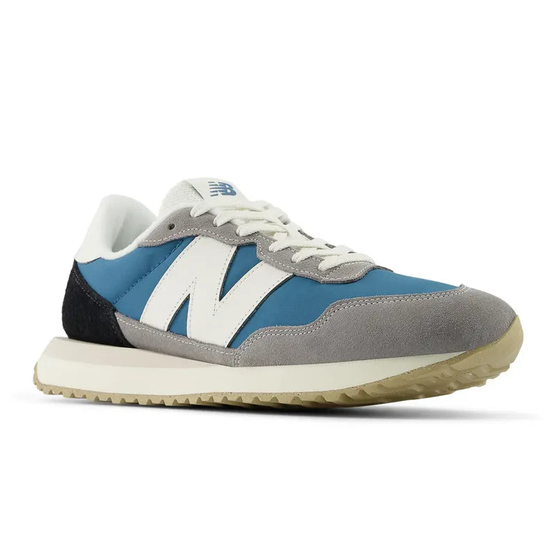 New Balance 237 V1 sneakers in blue, gray, and white with suede overlays, mesh panels, and gum outsole, angled front view.