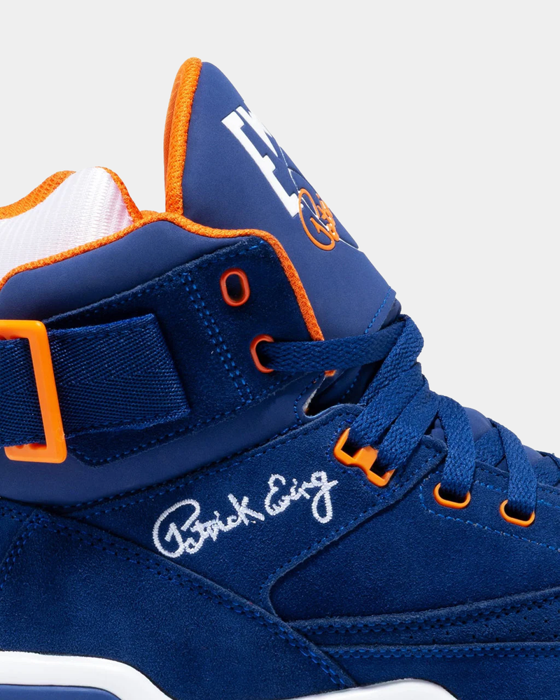 Ewing Athletics 33 HI OG sneakers in blue suede with orange accents, white Patrick Ewing signature, and mid-top profile, side view close-up.
