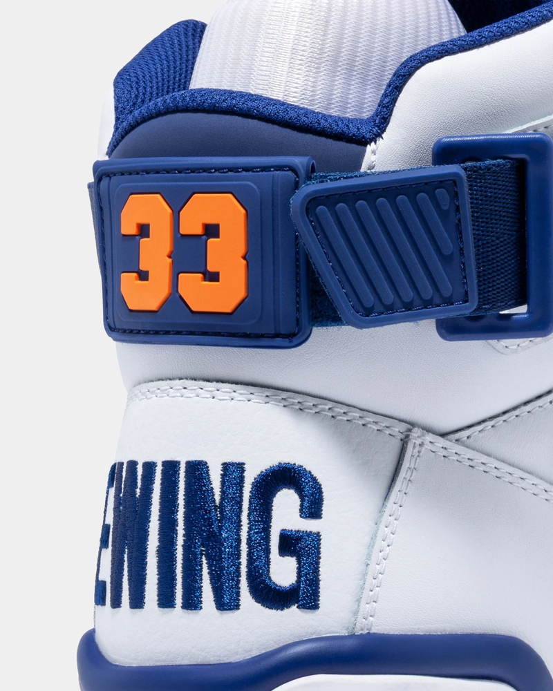 Ewing Athletics 33 HI OG sneakers in white leather with blue accents, orange "33" strap detail, and embroidered blue "EWING" branding, back view.