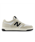 New Balance 480 sneakers in beige and white with black logo and perforated toe box, side view.