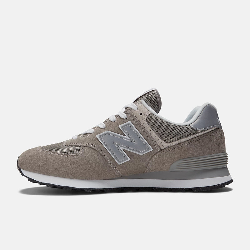 New Balance 574 Core sneakers in taupe suede with gray mesh panels and iconic "N" logo, side profile view.