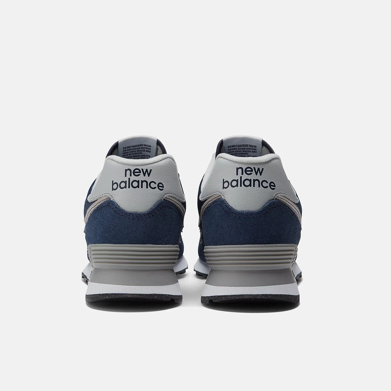 New Balance 574 Core sneakers back view showing heel design with navy blue suede, gray accents, and textured midsole.
