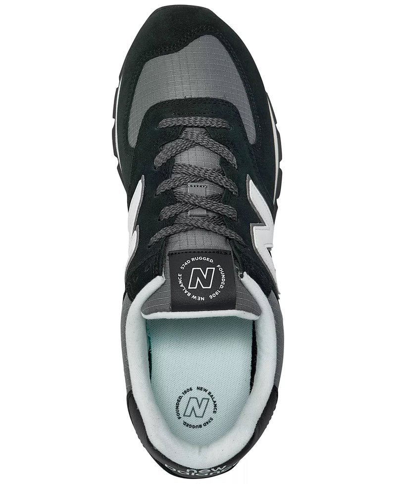 New Balance 574 Rugged sneakers, top view showing black suede overlays, gray ripstop material, and padded tongue with branding.