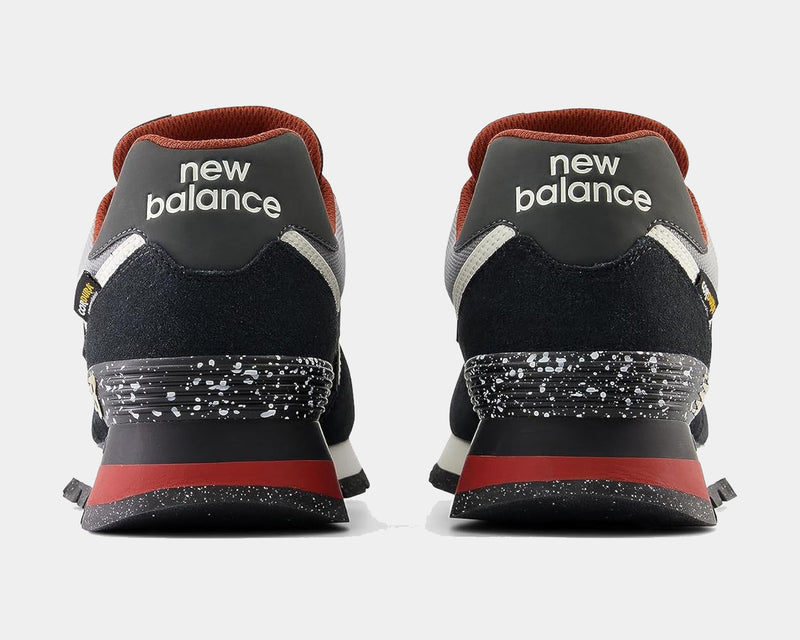 New Balance 574 Rugged sneakers back view showcasing black suede uppers, red accents, and speckled heel detailing.