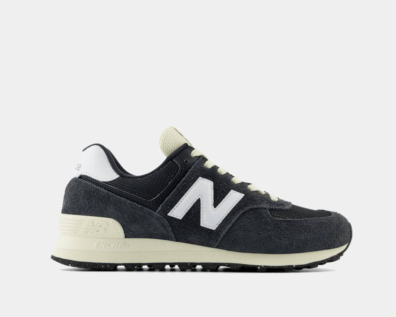 New Balance 574 sneakers in black suede and mesh with white logo and cream midsole, side view.