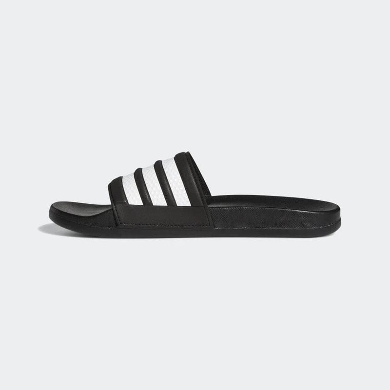Adidas Adilette Comfort slide sandals in black with white textured stripes on strap, side view.