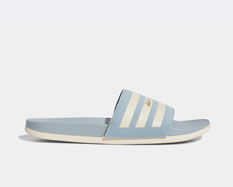Adidas Adilette Comfort slides in light blue with white stripe accents and cushioned sole, side view.