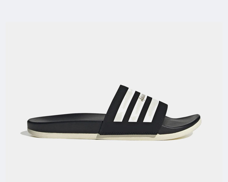 Adidas Adilette Comfort slides in black with white stripe detail and contoured footbed, side view.
