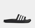 Adidas Adilette Comfort slide sandals in black with white stripes and cushioned footbed, side view.