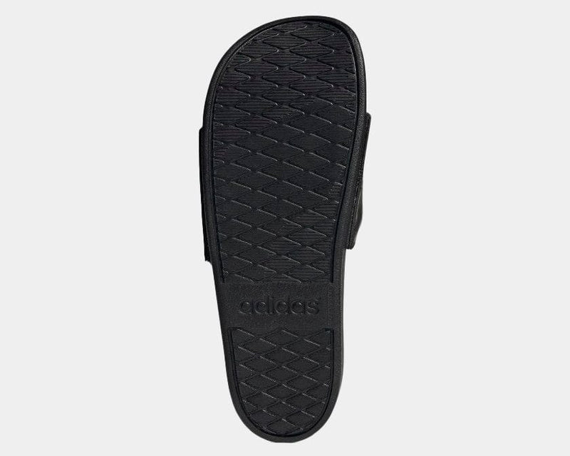 Adidas Adilette Comfort sandals black outsole with textured grip pattern and embossed Adidas logo, bottom view.