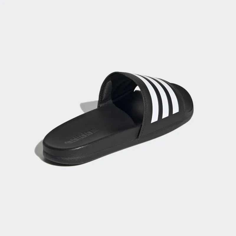Adidas Adilette Comfort slides in black with white stripe detail, featuring contoured footbed and lightweight design, angled side view.