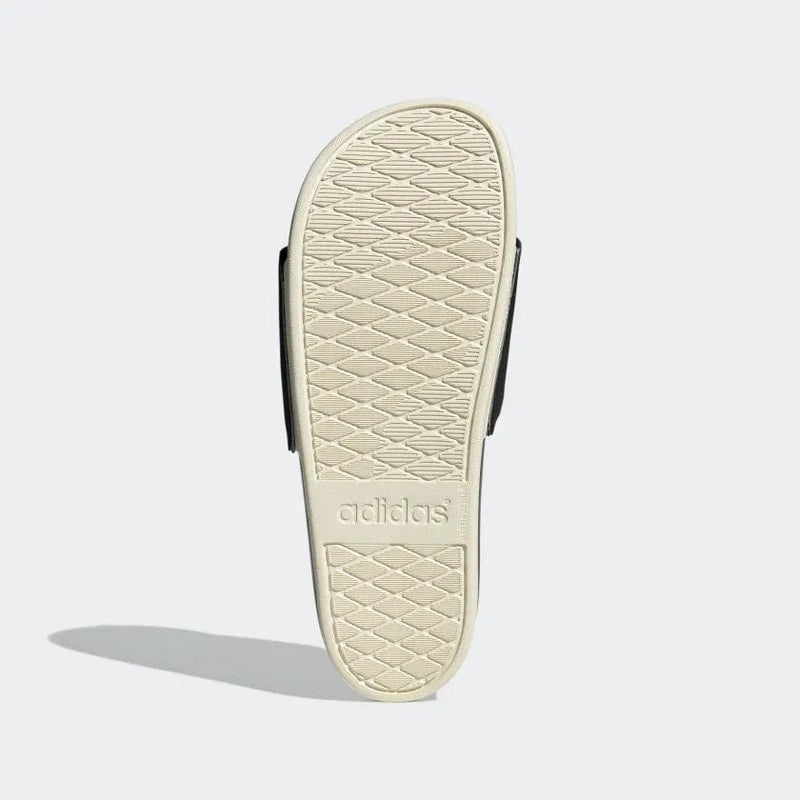 Adidas Adilette Comfort sandals sole view showing beige textured outsole with Adidas branding.