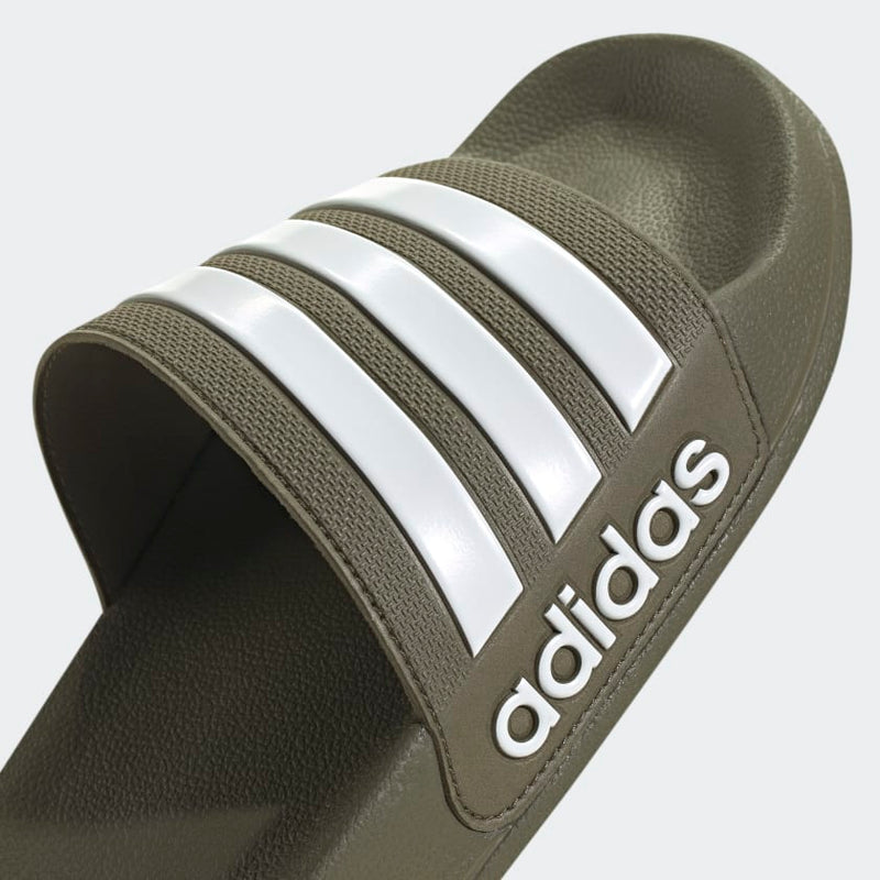 Adidas Adilette Comfort slides in olive green with white three-stripe design and textured footbed, angled close-up view.