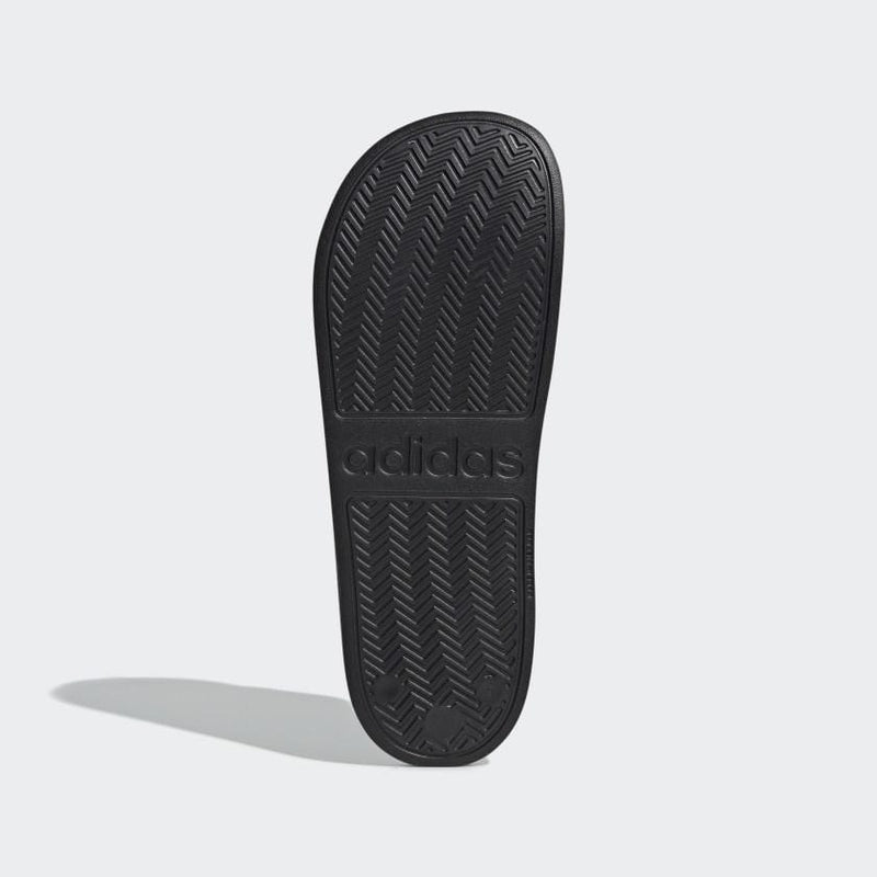 Adidas Adilette Shower Slides outsole showing black rubber with embossed Adidas logo and zigzag traction pattern.