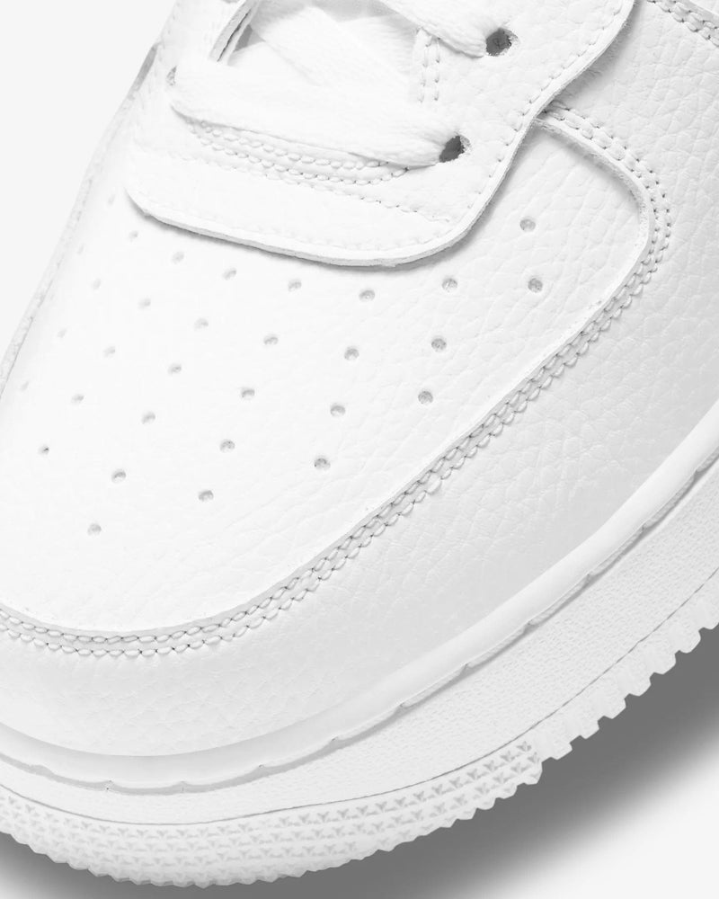 Nike Air Force 1 07 High sneaker with white leather upper, perforated toe box, and textured outsole, close-up view.
