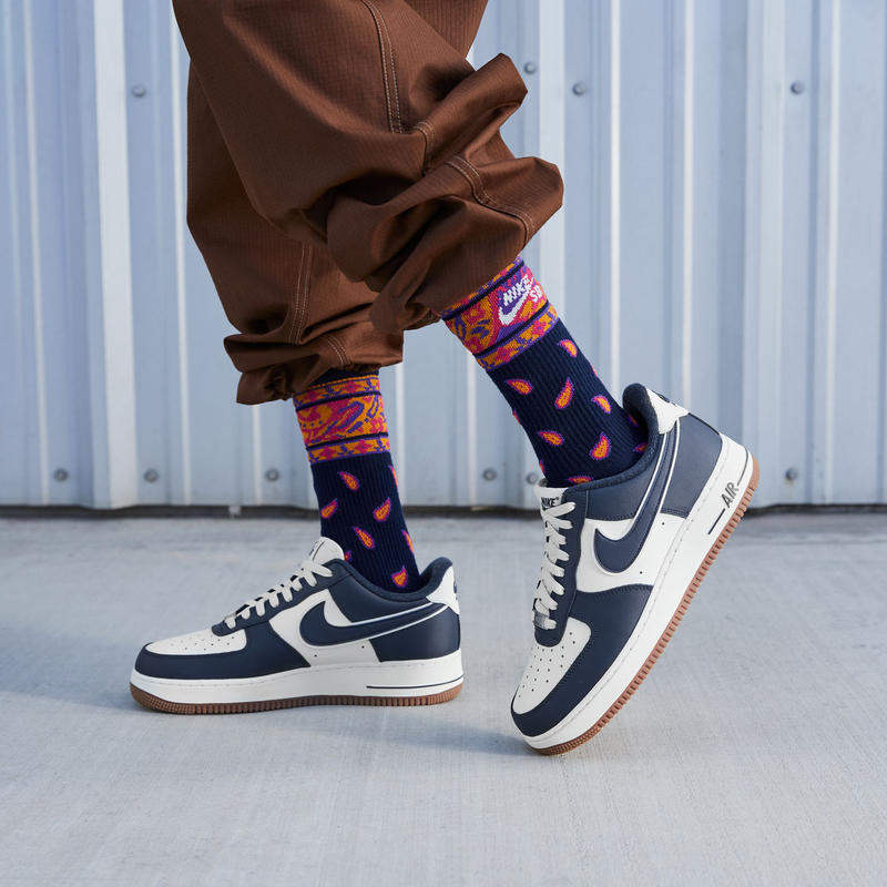 Nike Air Force 1 '07 LV8 sneakers in navy blue and white with perforated toe box and gum rubber outsole, worn in lifestyle setting.