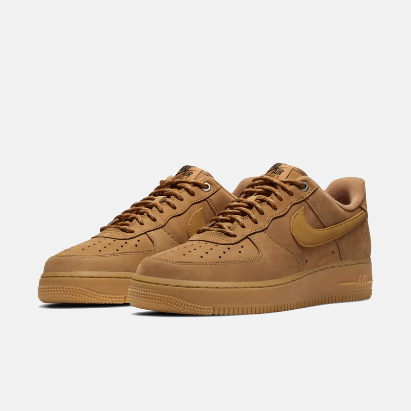 Pair of brown Nike Air Force sneakers on a light gray background