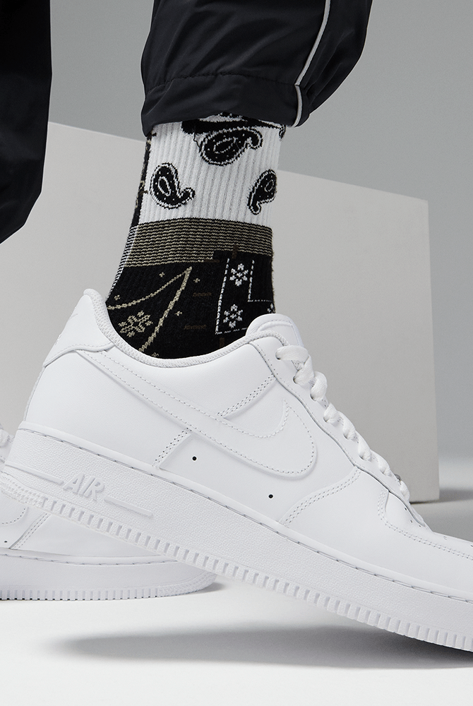 Nike Air Force 1 '07 sneakers in white leather with classic perforated toe box and embossed "Air" detail on midsole, side view worn.