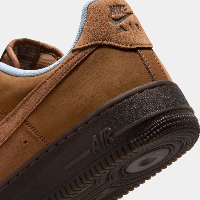 Nike Air Force 1 '07 sneakers in brown leather and suede with embossed heel logo, black outsole, side view close-up.