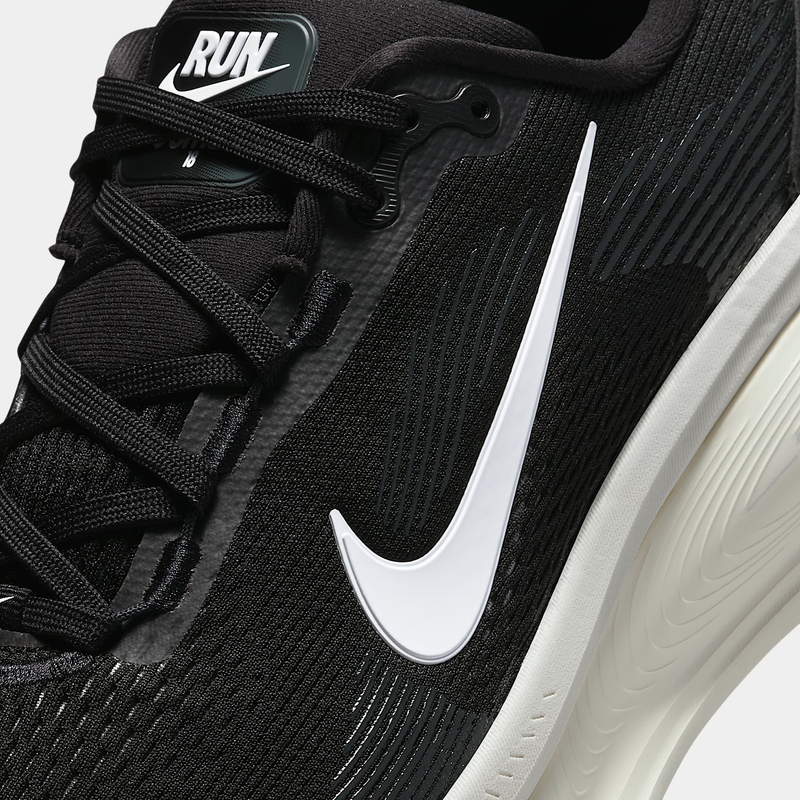 Nike Air Zoom Vomero 18 running shoes in black with white swoosh logo and textured mesh upper, close-up side view.