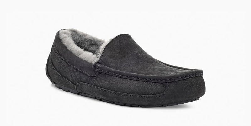 UGG Ascot Matte Leather slippers in black with matte finish leather upper, gray plush lining, and moc-toe stitching, side angle view.