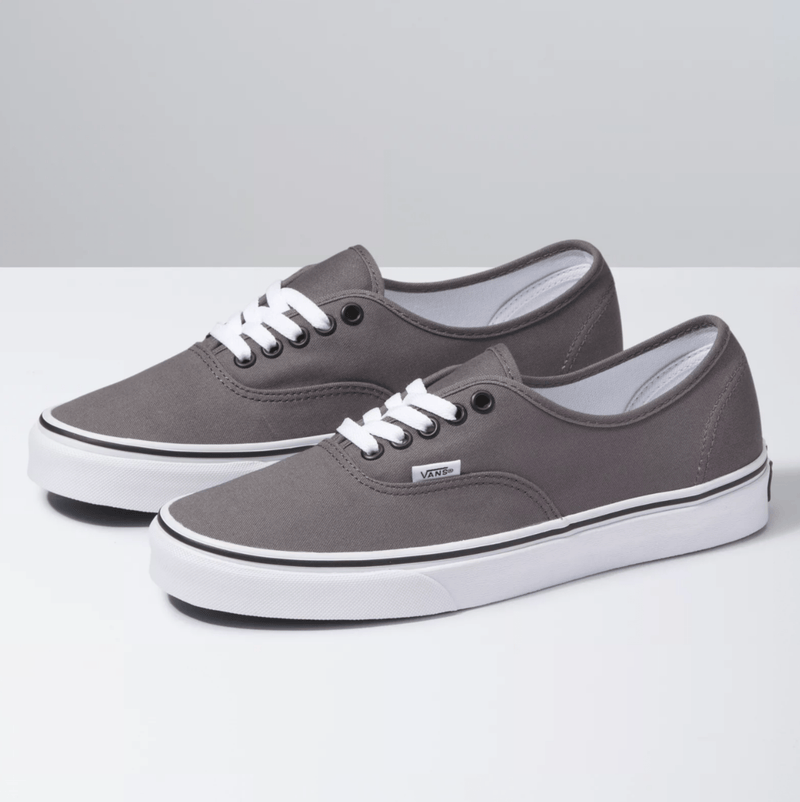 Vans Authentic sneakers in gray with canvas upper, white laces, metal eyelets, and vulcanized rubber outsole, angled side view.