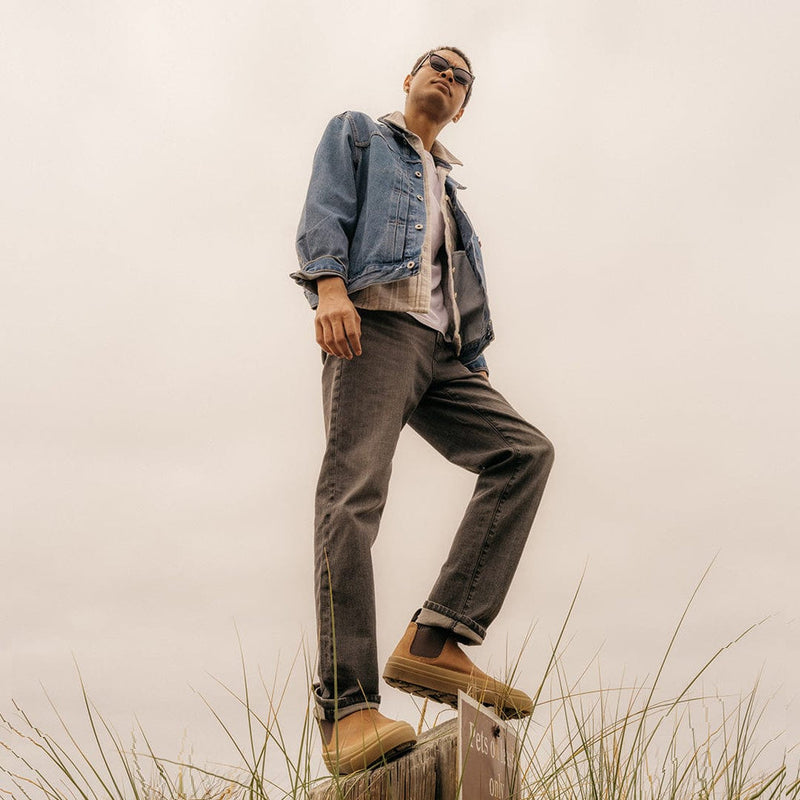 SeaVees Ballard Boot in tan with minimalist design and sturdy construction, worn outdoors on a wooden post for lifestyle context