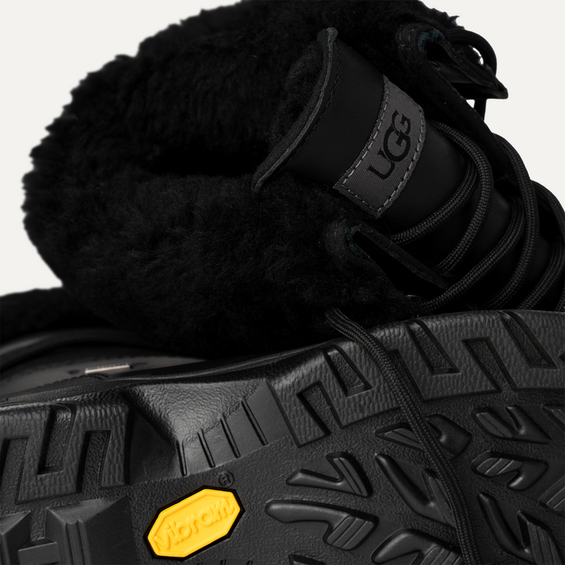 UGG Butte boots in black with sheepskin lining, leather upper, and Vibram outsole, close-up view of details.