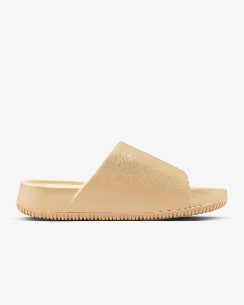 Nike Calm Slide sandals in beige with synthetic upper and textured sole, side view.