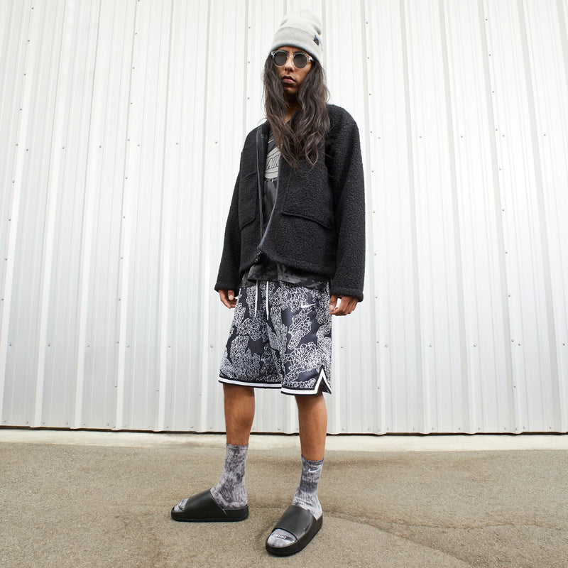 Nike Calm Slide sandals in black with contoured footbed worn with socks, lifestyle context.
