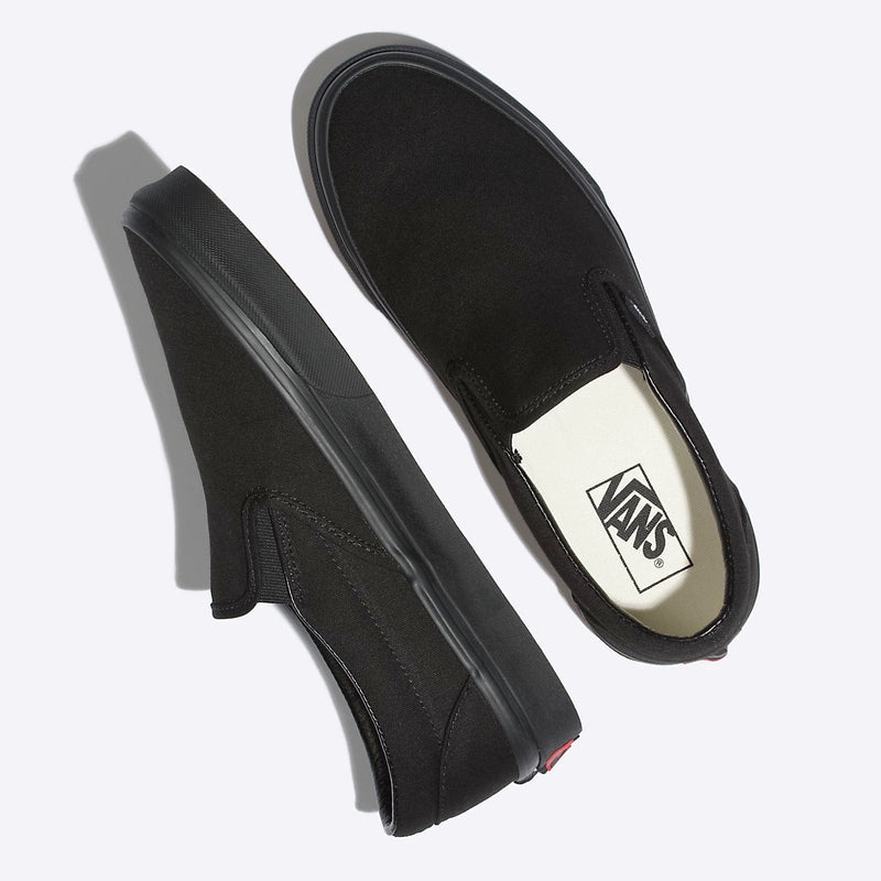 Vans Classic Slip On shoes in black canvas with elastic side accents and rubber outsole, top and angled side view.