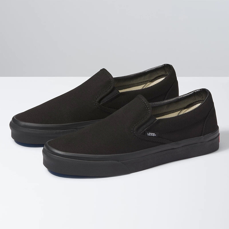 Vans Classic Slip On shoes in black with canvas upper and elastic side accents, side angle view.
