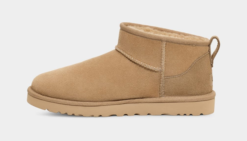 UGG Classic Ultra Mini Boot in chestnut suede with sheepskin lining and pull tab, side view.