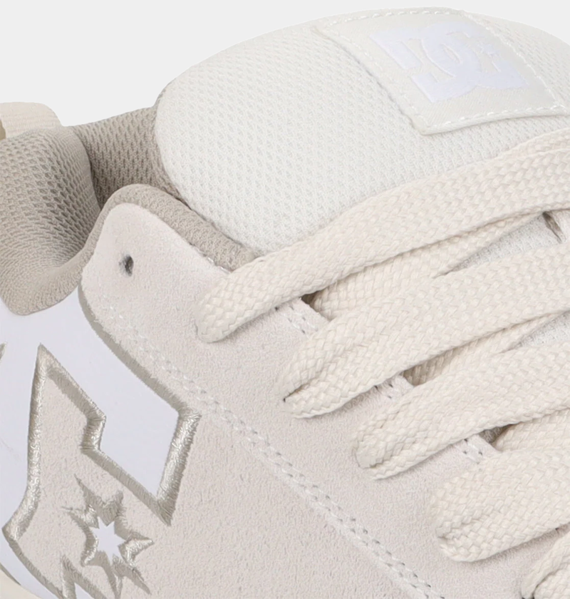 DC Footwear Court Graffik SE skate shoes in beige suede with metallic silver logo detailing and white mesh tongue, close-up view.