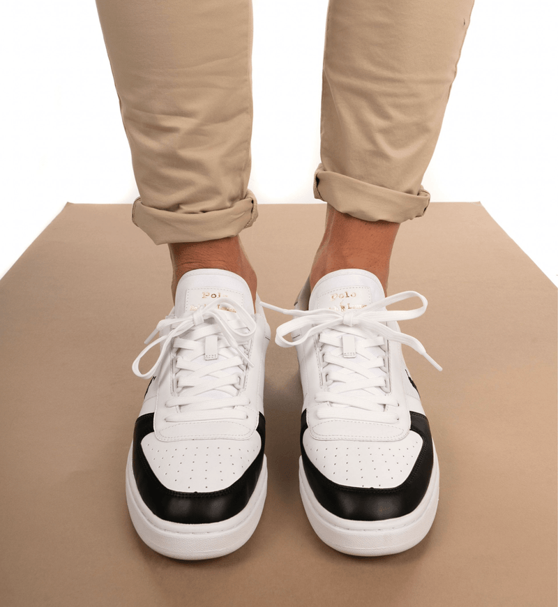 Polo Ralph Lauren Court PP sneakers in white leather with black toe cap accents, gold logo details, and lace-up closure, front view worn.