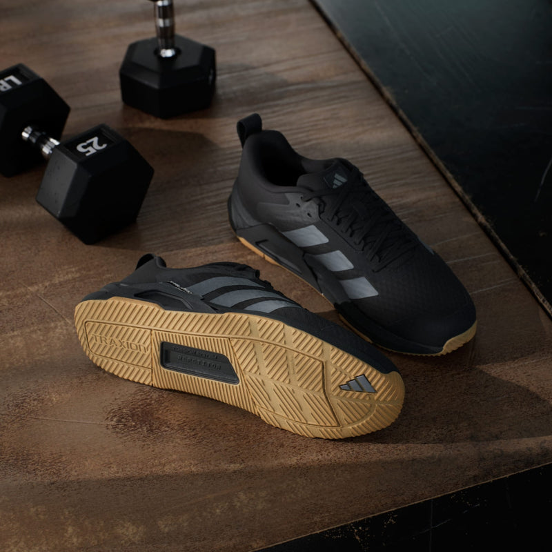 Adidas Dropset Control Trainer shoes in black with gum soles, mesh upper, and signature three-stripe design, angled lifestyle view.