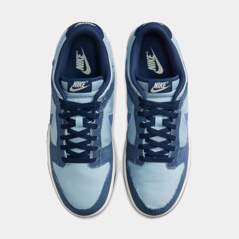 Nike Dunk Low Retro SE sneakers in light blue and navy blue denim material with white midsoles, top view showing lace-up design and branding.