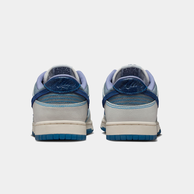 Nike Dunk Low Retro SE sneakers in white and blue with textured heel details and rubber outsole, back view.