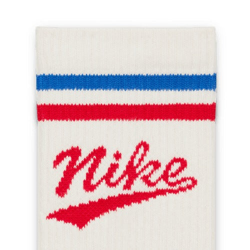 Nike Everyday Plus Crew Socks in white with red Nike script logo and red and blue striped design, close-up view.