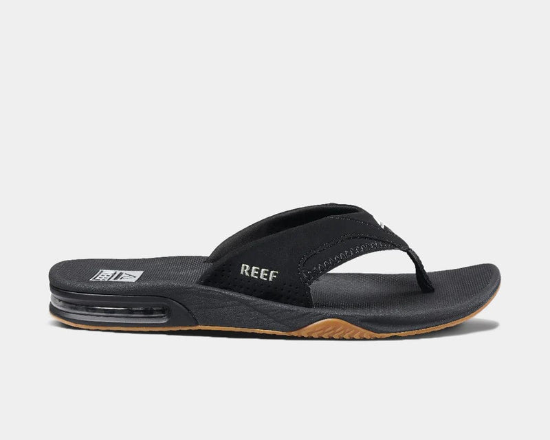 Reef Fanning Flip Flops in black with synthetic upper, contoured footbed, and bottle opener in sole, side view.
