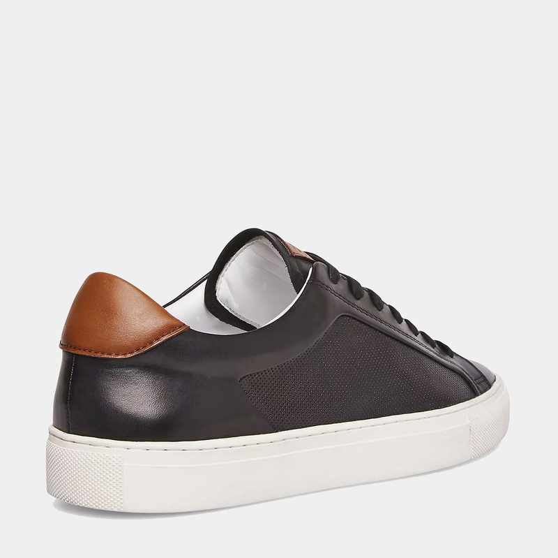 Steve Madden Finneas sneakers in black leather with textured side panel, brown heel accent, and white rubber sole, back view.
