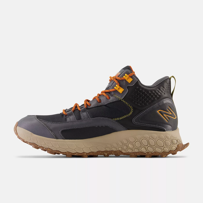 New Balance Foam X Hierro Mid GTX hiking shoes in dark gray with orange laces, Gore-Tex upper, and rugged beige outsole, side view.