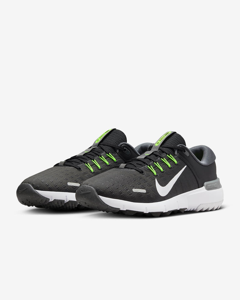Nike Free Golf Next Nature shoes in black with neon green laces, mesh upper, and white sole, angled front view.