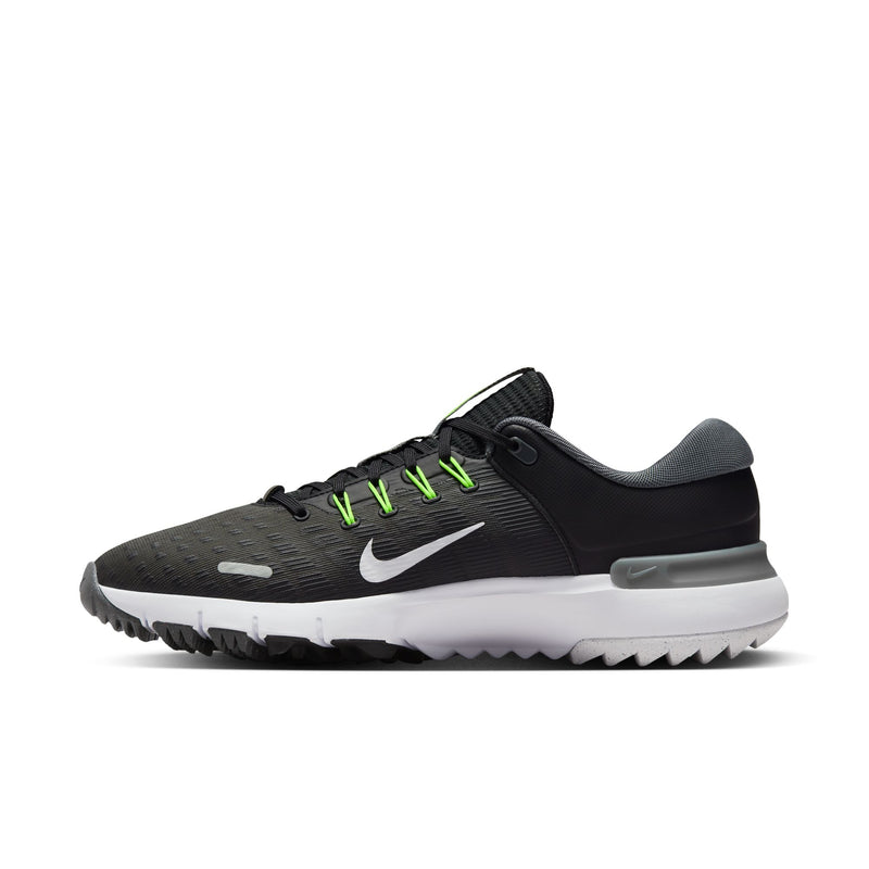 Nike Free Golf Next Nature golf shoes in black with bright green laces, white midsole, and textured outsole, side view.