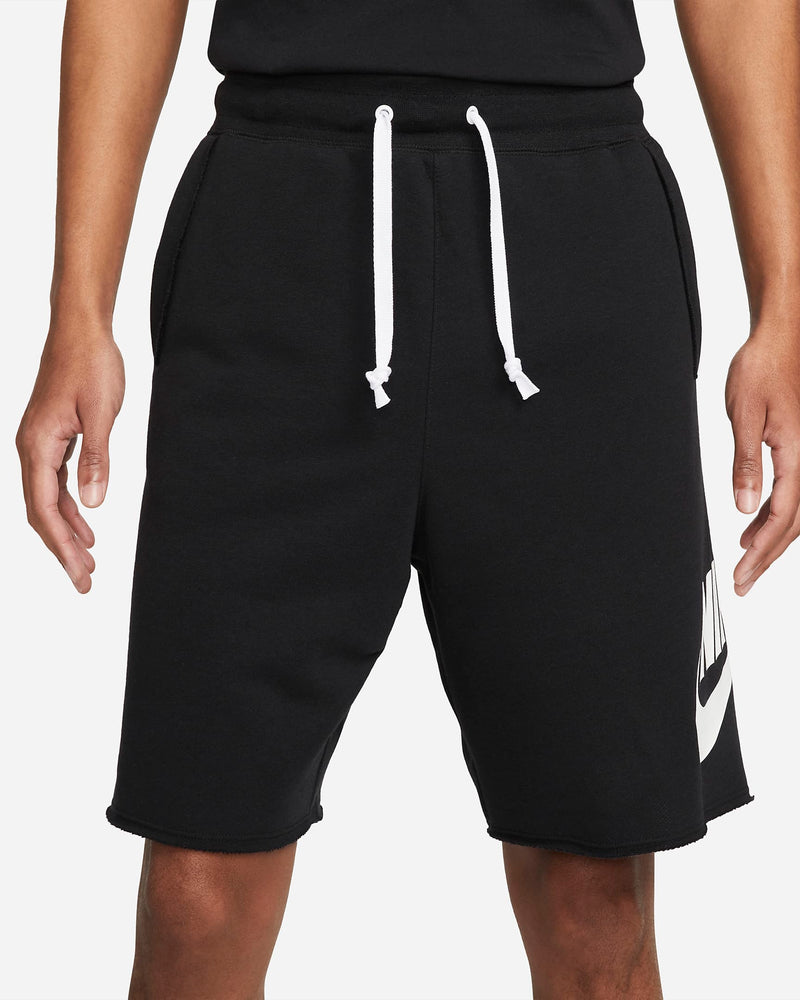 Nike French Terry Alumni Shorts, black with raw-edge hems, adjustable white drawstring waistband, and Nike logo on the leg, front view.