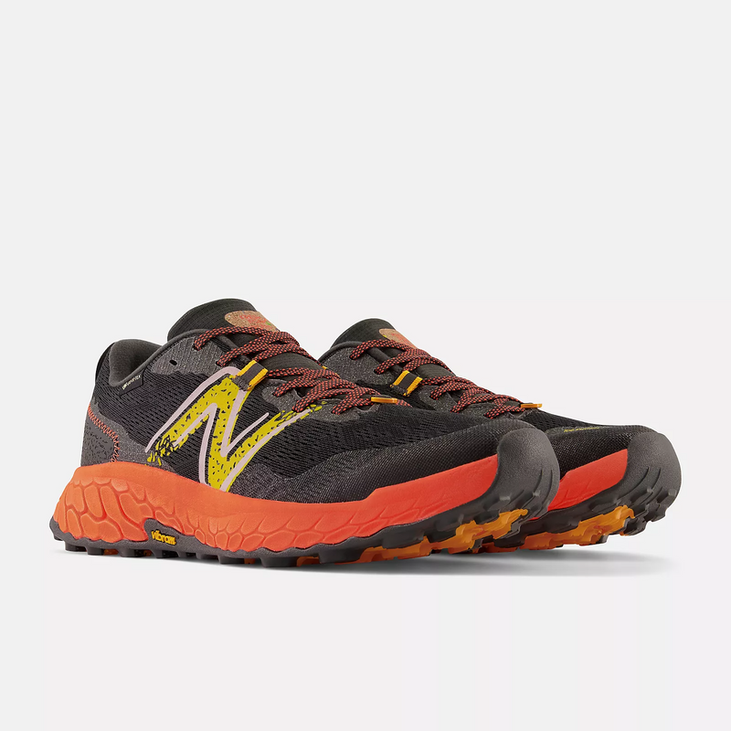 New Balance Fresh Foam Hierro v7 trail running shoes in black with orange midsole, yellow logo accents, and Vibram outsole, front-side view.