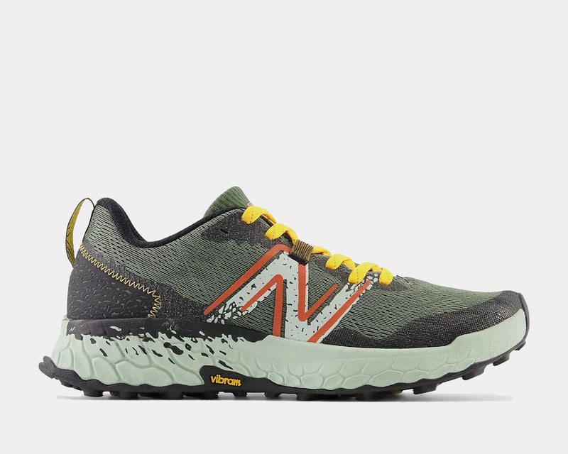 New Balance Fresh Foam Hierro v7 trail running shoes, side view showing green mesh upper, orange and yellow accents, Fresh Foam midsole, and Vibram outsole.