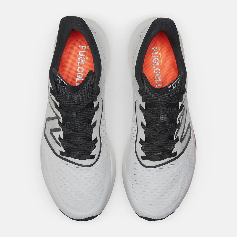 New Balance FuelCell Rebel v3 running shoes in white with black laces, orange insoles, and a breathable mesh upper, top view.