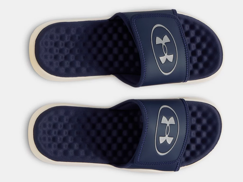 Under Armour Ignite Pro 8 Slides in navy blue with textured foam footbed and adjustable strap featuring logo detail, top view.