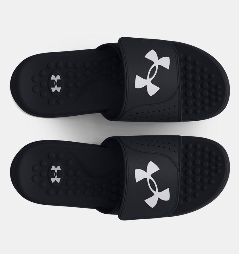 Under Armour Ignite Pro SL slides in black with white logo, cushioned footbed with textured massage nodes, top view.